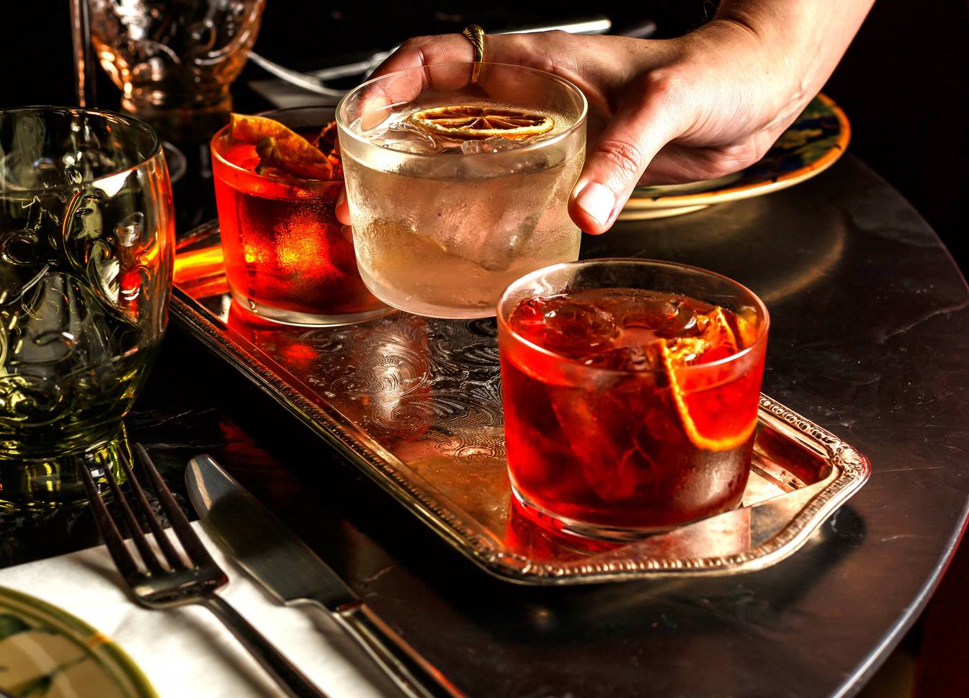 Bandeja com três coquetéis à base de Negroni servidos em copos baixos